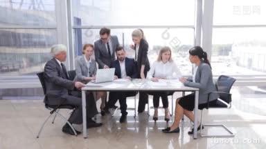 <strong>业务团队</strong>坐在桌子旁边，笔记本电脑和文件在办公室